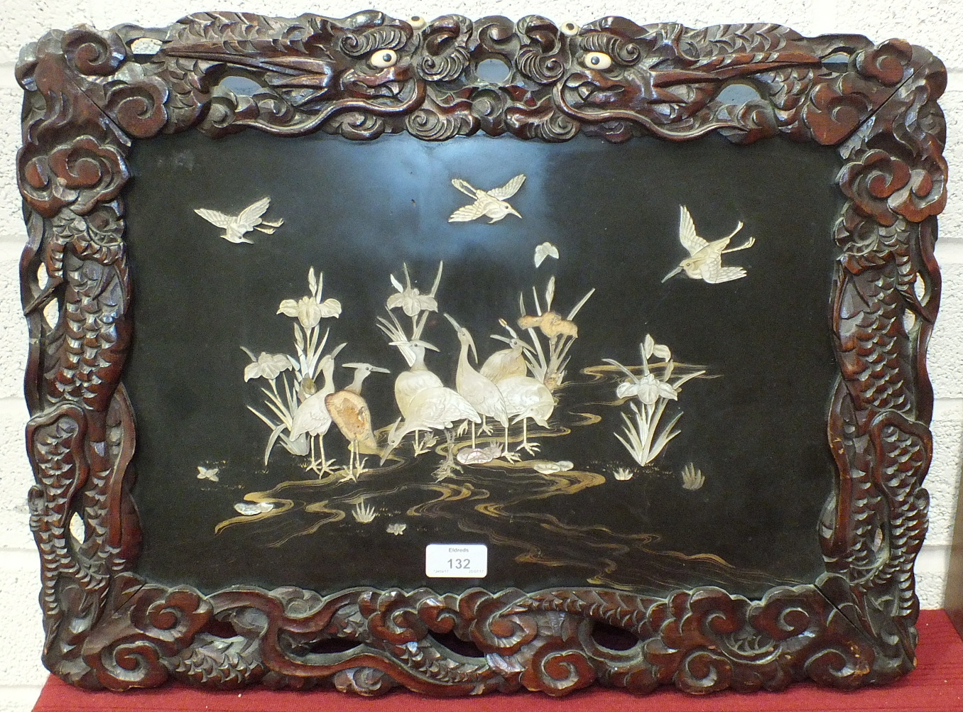 A Chinese lacquered panel depicting cranes, within a pierced wood frame carved with a dragon, 43 x