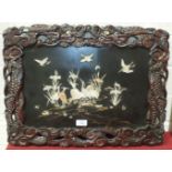 A Chinese lacquered panel depicting cranes, within a pierced wood frame carved with a dragon, 43 x