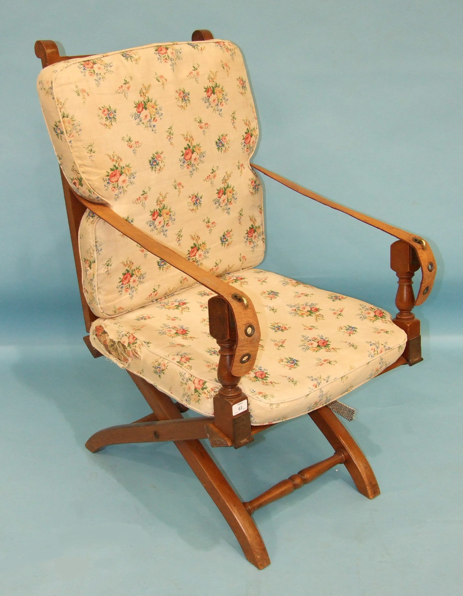 An Edwardian folding campaign chair, the caned back retained by leather-strap arms, on X-frame