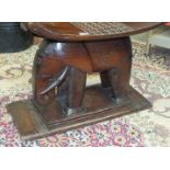 A late-19th/early-20th century carved elephant stool, the dished seat carved with symmetric