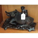 An early 20th century carved hardwood figure of a water buffalo (af) with a figure on its back,