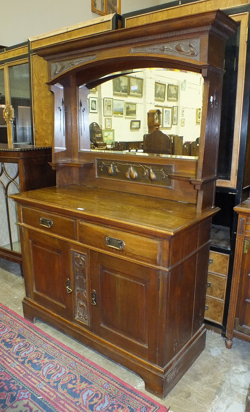 An early-20th century oak sideboard in the Art Nouveau style, the mirrored back with copper panel of