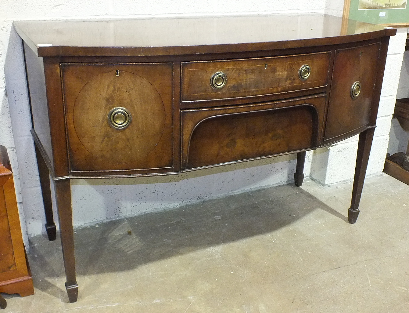 A Georgian mahogany bow-fronted sideboard fitted with two central drawers, flanked by cupboard