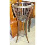 A stained wood basket-shaped plant stand raised on three splayed legs united by an undertier, 93cm