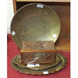 A brass circular shallow dish, 33cm diameter, two small decorated brass trays and a small carved