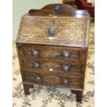 A carved oak bureau, the fall front above three drawers with lion mask handles, 75cm wide, 110cm