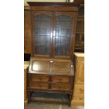 An early-20th century oak bureau/bookcase, the upper bookcase fitted with a pair of leaded light