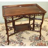 An Oriental hardwood tray-top table with pierced frieze, on folding stand united by an undertier, 81
