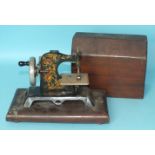 A German tinplate toy sewing machine in wood case, (af).