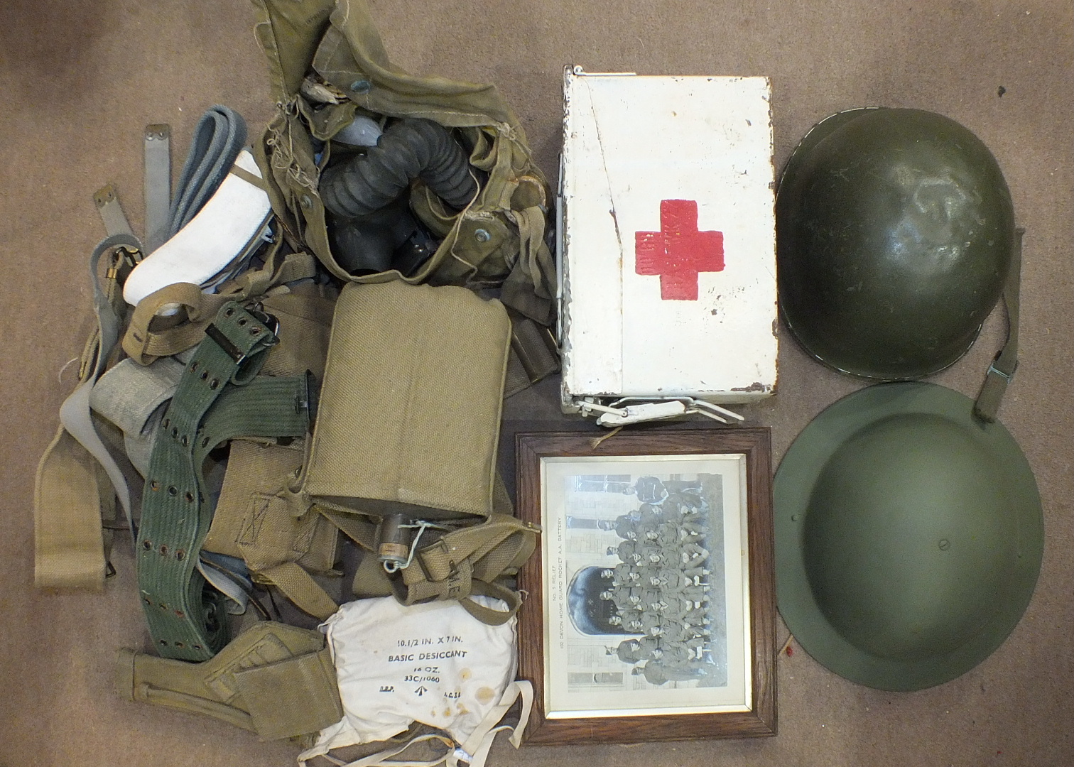 A collection of WWII webbing, water bottle, tin helmet, American tin helmet and a photograph of