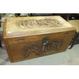 A mid-20th century camphor wood chest with carved sides and lid depicting figures, sailing ships and