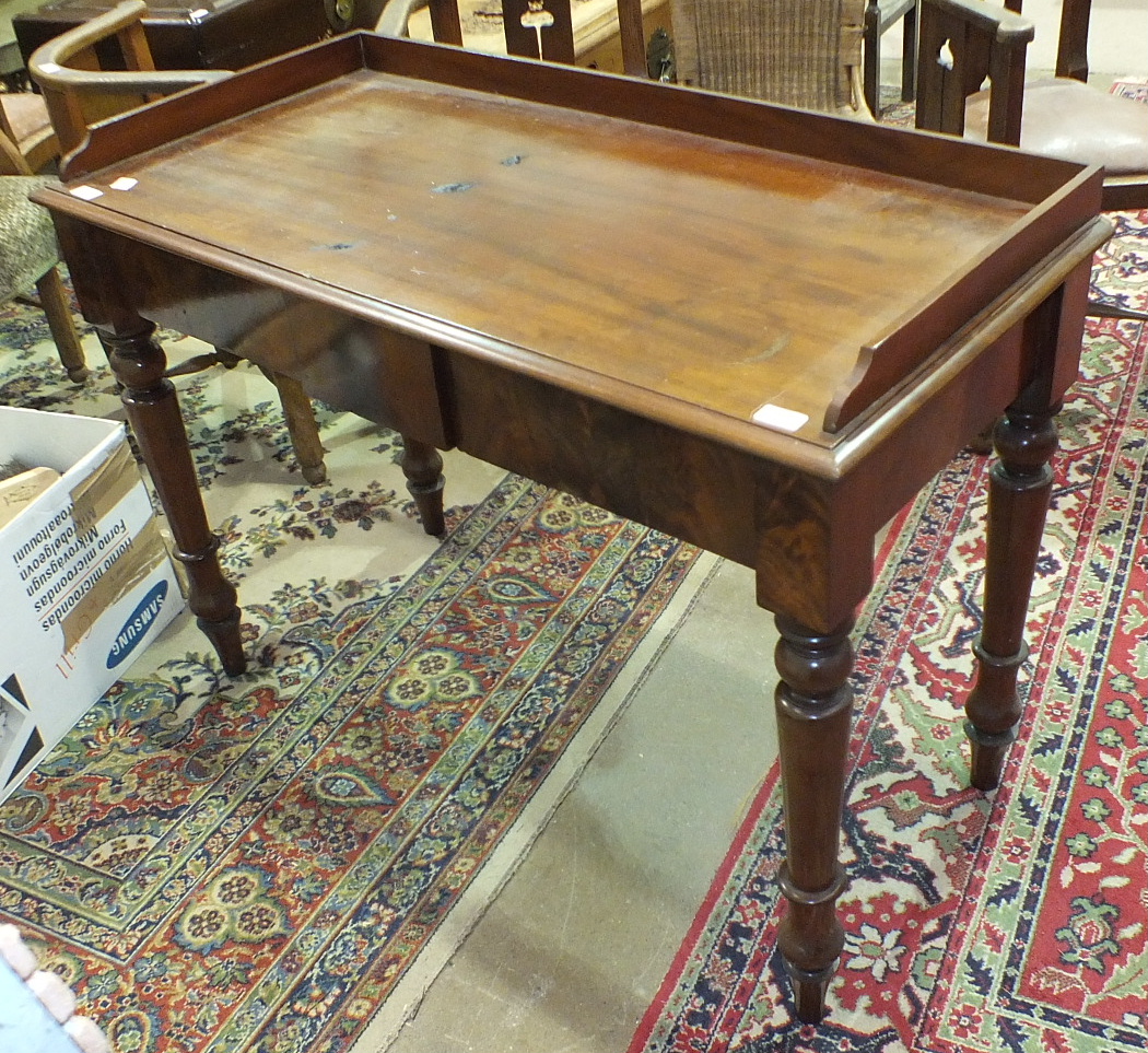 A Victorian two-drawer side table with galleried rectangular top, on turned legs, 112cm wide.