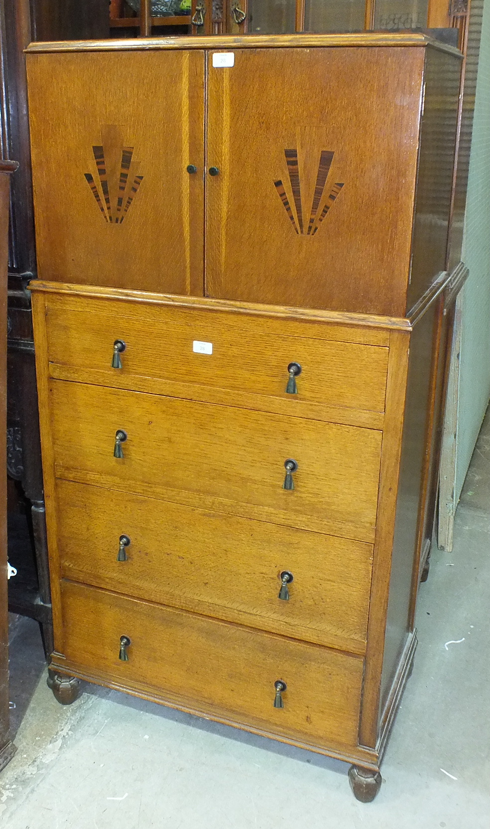 A 1920's/30's oak tallboy having a pair of doors with Art Deco inlaid decoration above four drawers,