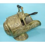 A pressed brass coal scuttle decorated with foliage, together with a coal shovel, both with turned