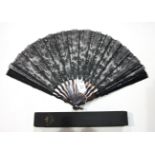 A late-19th century large black lace fan with tortoiseshell guards carved to represent stems, wavy