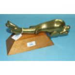 A large brass dolphin door knocker, 28cm long, on wooden plinth.