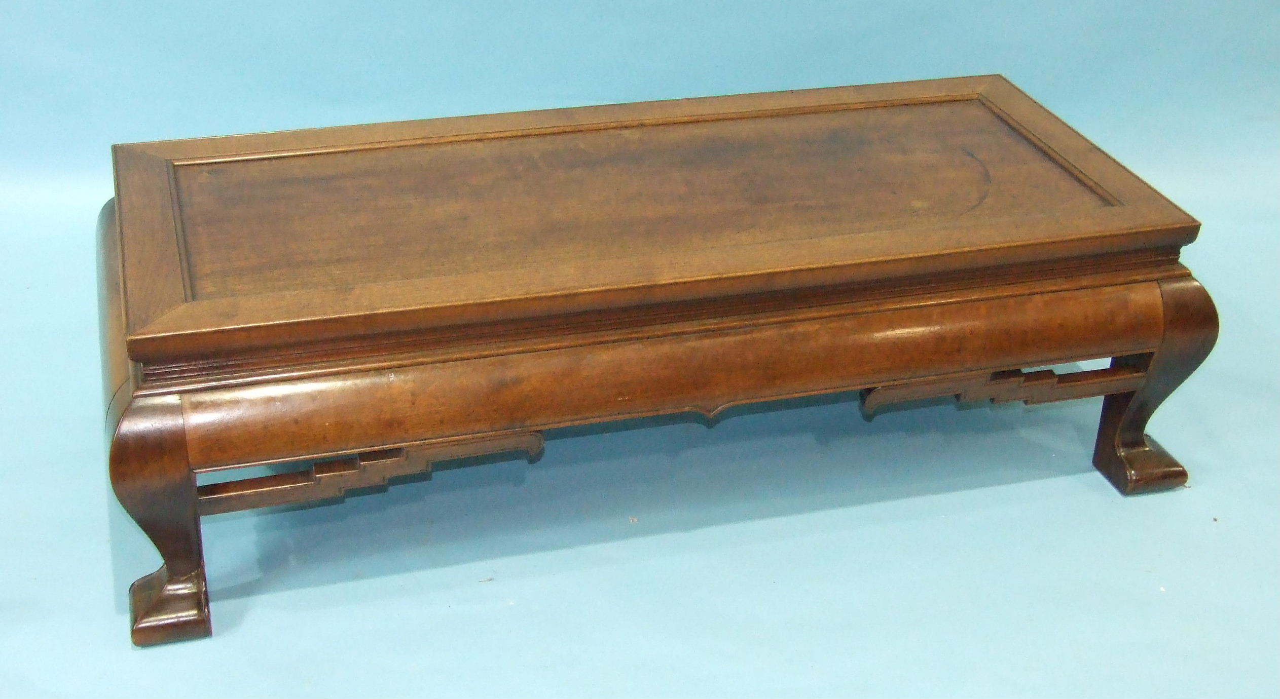 An early-20th century Oriental hardwood low table, the rectangular panelled top and convex pierced