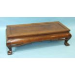 An early-20th century Oriental hardwood low table, the rectangular panelled top and convex pierced