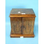 A Victorian figured walnut humidor, the rectangular top above a pair of inlaid doors enclosing three