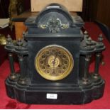 A black slate mantel clock of architectural form, the brass dial with Arabic numerals, the gong-