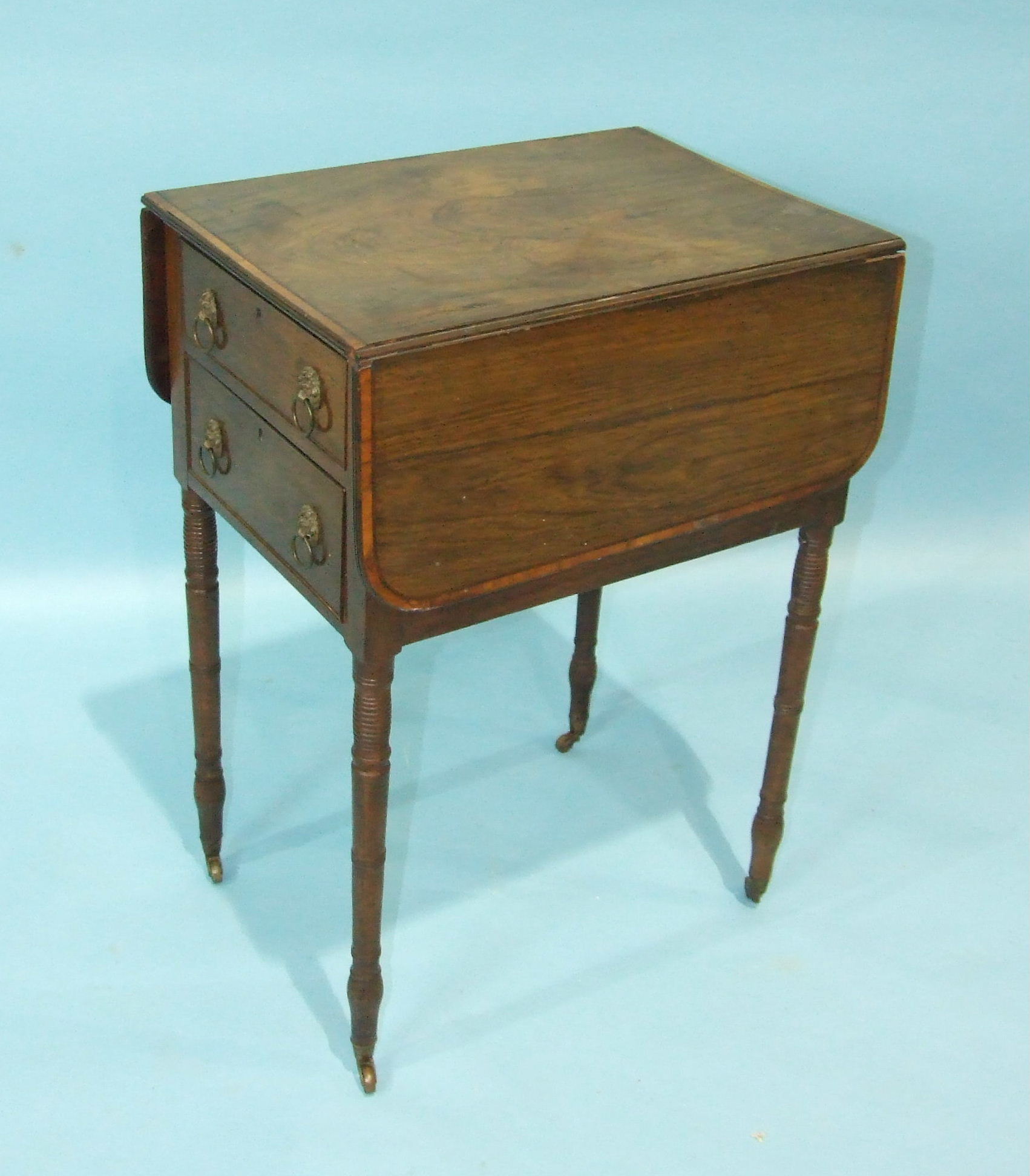 An early-19th century rosewood two-drawer work table, on turned legs with castors, (in need of