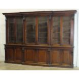 A large Victorian mahogany breakfront bookcase, the moulded stepped cornice supported by carved