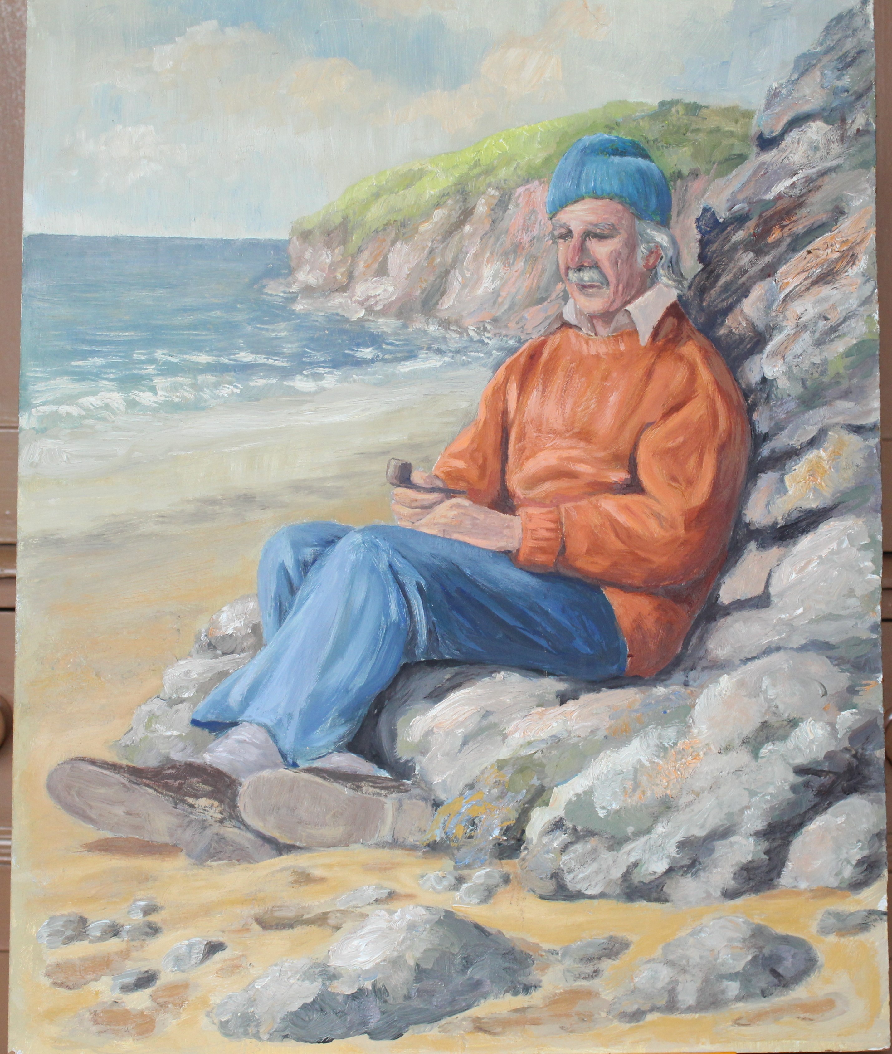 •AN ELDERLY MAN SITTING AGAINST ROCKS ON A BEACH CONTEMPLATING HOLDING A PIPE Signed unframed oil on