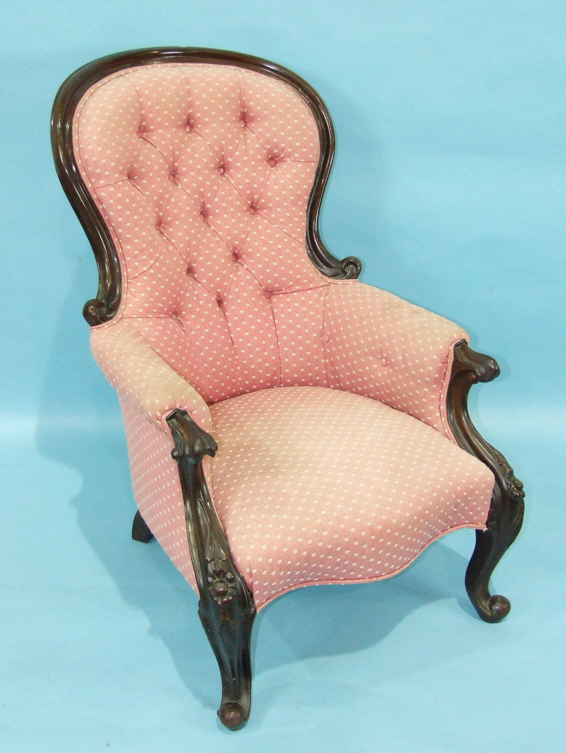A Victorian button-back salon chair with heavily-carved frame and serpentine seat.