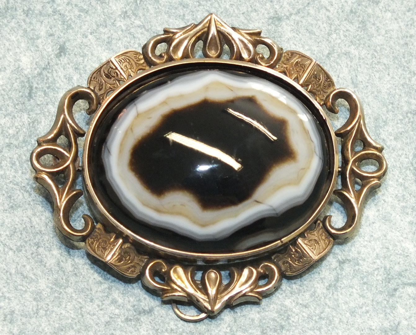 A Victorian brooch set a large banded agate in scrolling mount, 6 x 5cm.