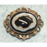 A Victorian brooch set a large banded agate in scrolling mount, 6 x 5cm.