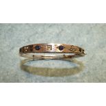An Edwardian hinged bangle, centrally set an old brilliant cut diamond between two pairs of