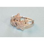 A modern 9ct white gold ring in the form of four diamond set stars between split shoulders, size