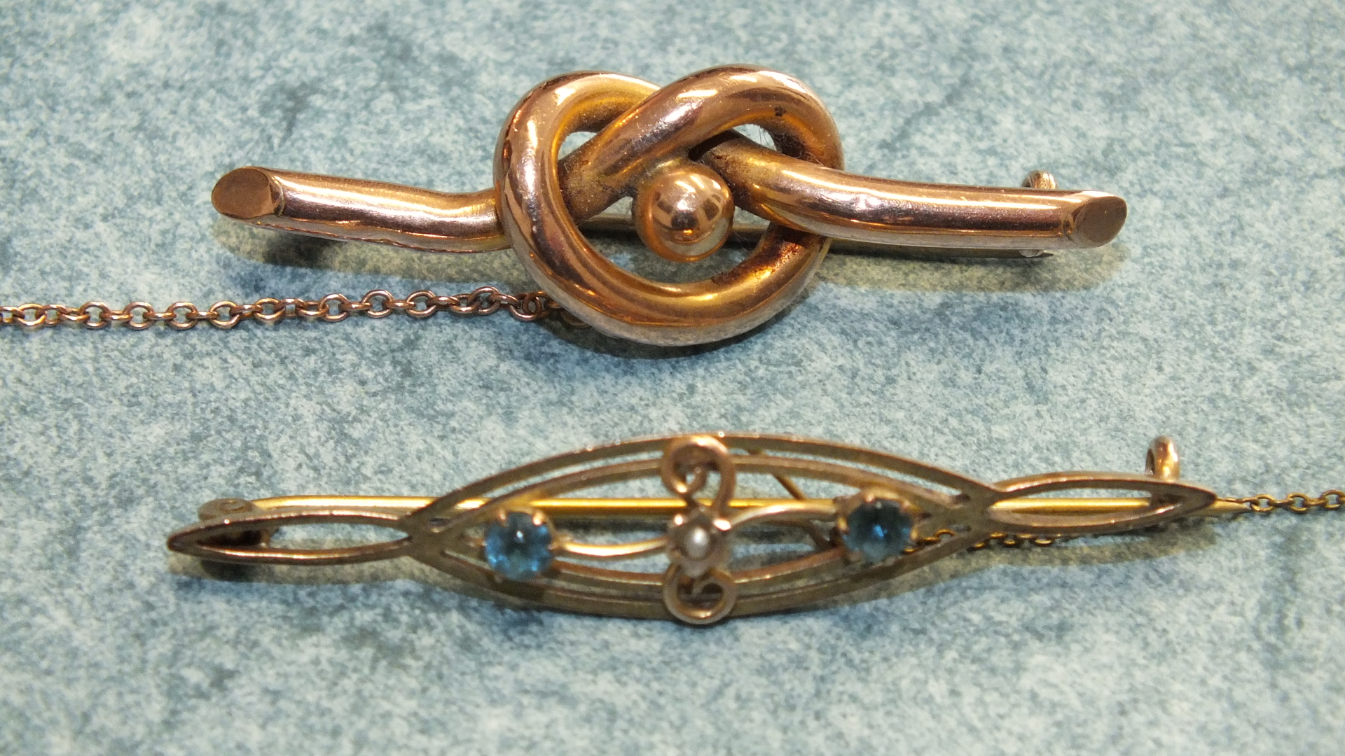 An Edwardian 9ct gold brooch set blue topaz and pearl and an unmarked knot brooch, total weight 5.