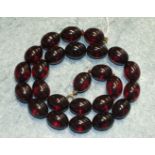 A cherry amber-type necklace of uniform sized ovoid beads, each 19 x14mm, 50cm long.