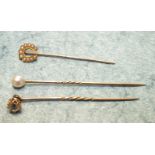 Three 19th century stick pins, one set a white paste stone, one a cultured pearl and one a pearl set