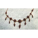 A 9ct gold garnet fringe necklace set nine graduated clusters of garnets with seven cluster pendants