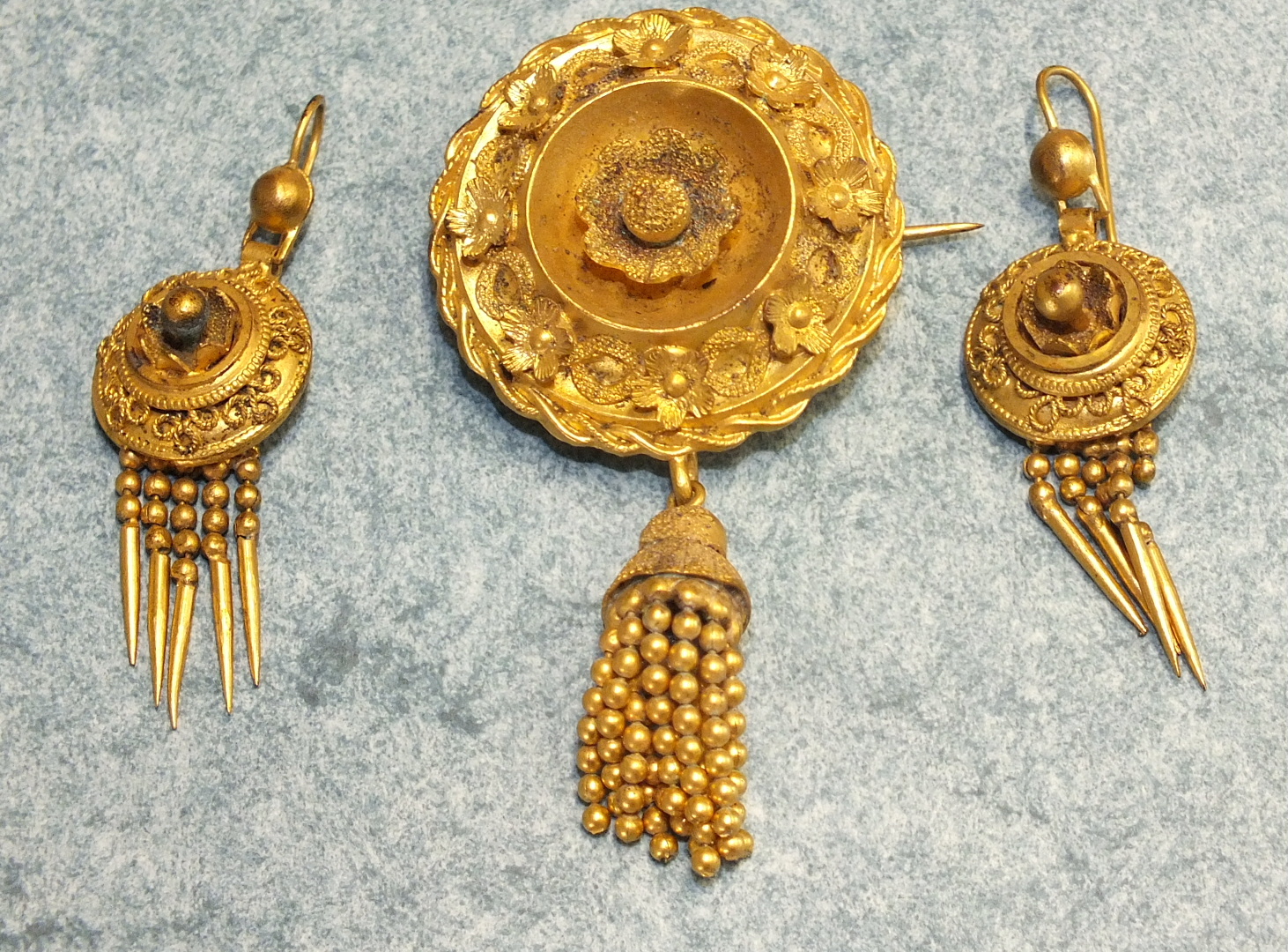 A Victorian gilt metal brooch with applied and cast decoration and tassel below and a pair of