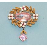 An oval wreath brooch/pendant centrally set an oval pink topaz of approximately 6.5cts within a gold