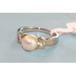 An 18ct white gold ring set a cultured pearl between two white stones, French marks, size L, 3.8g.