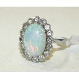 An opal and diamond cluster ring, claw set an oval opal of 13 x 9.5mm within a surround of sixteen