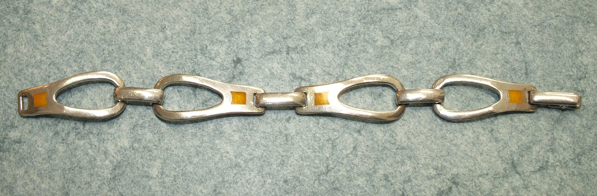 A silver Scandinavian silver style bracelet of rounded stirrup shaped links inset yellow squares,