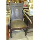 A 19th century oak Wainscot chair with carved decorated panel back, arms and square front legs.