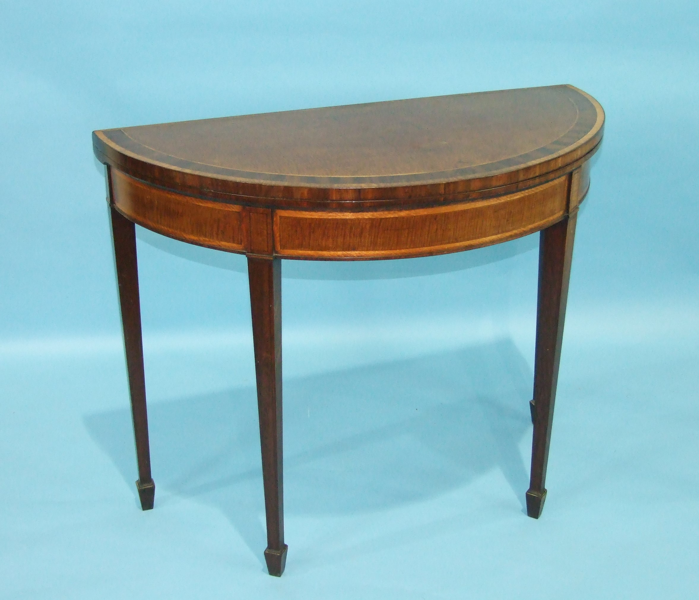 A George III mahogany and satinwood-banded fold-over card table, the half-round fold-over top raised