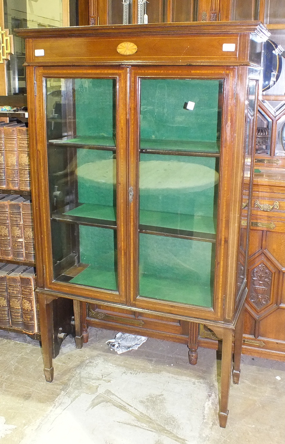 An Edwardian inlaid mahogany display cabinet, the rectangular top above a pair of glazed doors, on