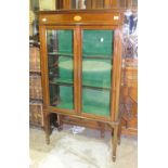 An Edwardian inlaid mahogany display cabinet, the rectangular top above a pair of glazed doors, on