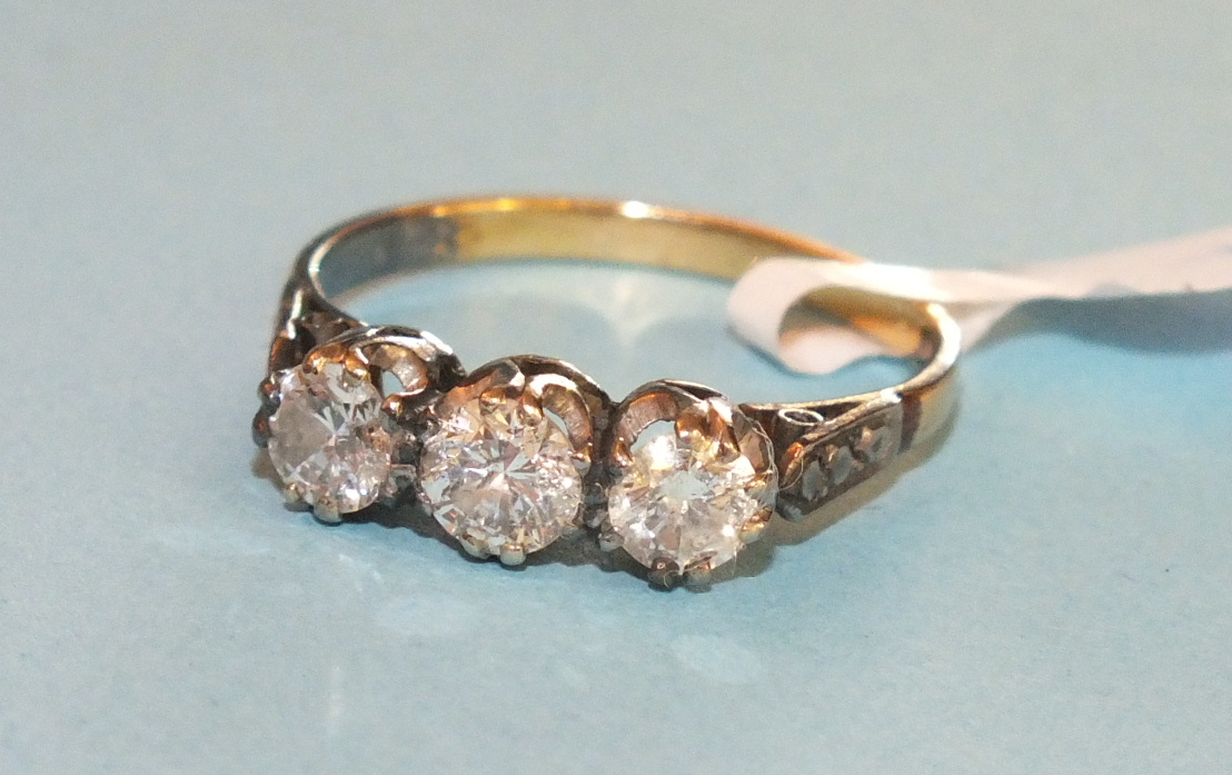 A three-stone diamond ring the brilliant cut diamonds in unmarked gold mount, size N, 2.2g.