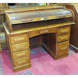 A 1920's/1930's oak roll-top knee-hole desk, the tambour above a central drawer flanked by seven