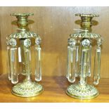 A pair of brass chenets, each candle sconce above a leaf-moulded disc with cut-glass drops, 20cm, (