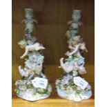 A pair of late-19th/early-20th century German porcelain candlesticks decorated with cherubs and