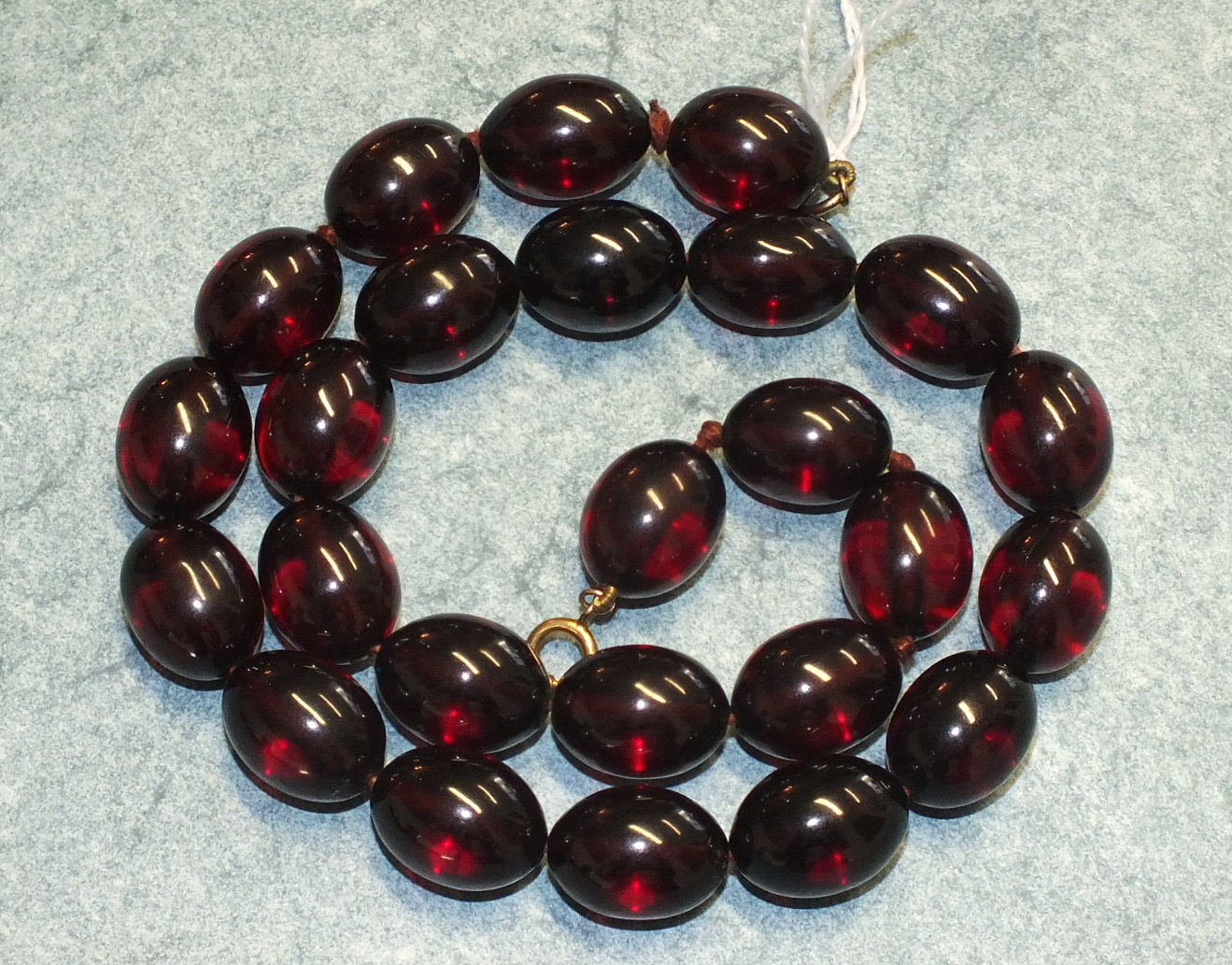 A cherry amber-type necklace of uniform sized ovoid beads, each 19 x14mm, 50cm long.